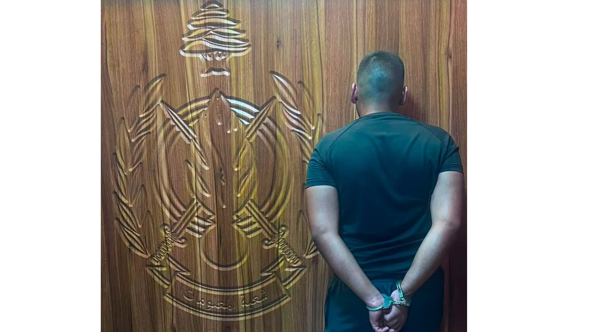 A detainee photographed from behind in front of an Internal Security Forces emblem